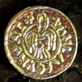 Stylized bird on a gold-colored Raven Penny replica
