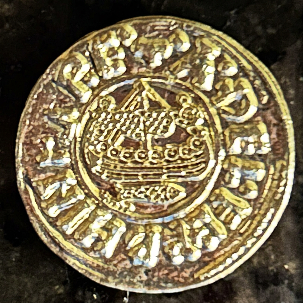 Crown-like reverse design on a gold-colored Raven Penny replica